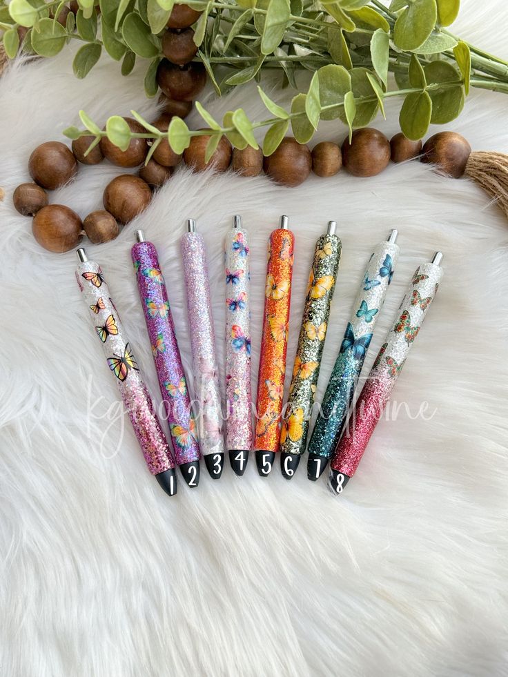 six different colored pens sitting on top of a white fur covered floor next to nuts