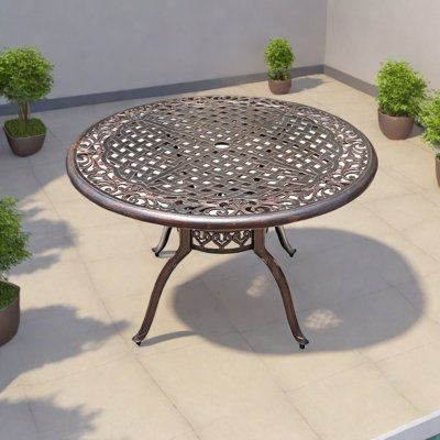 an outdoor table with potted plants on the ground in front of a wall and floor