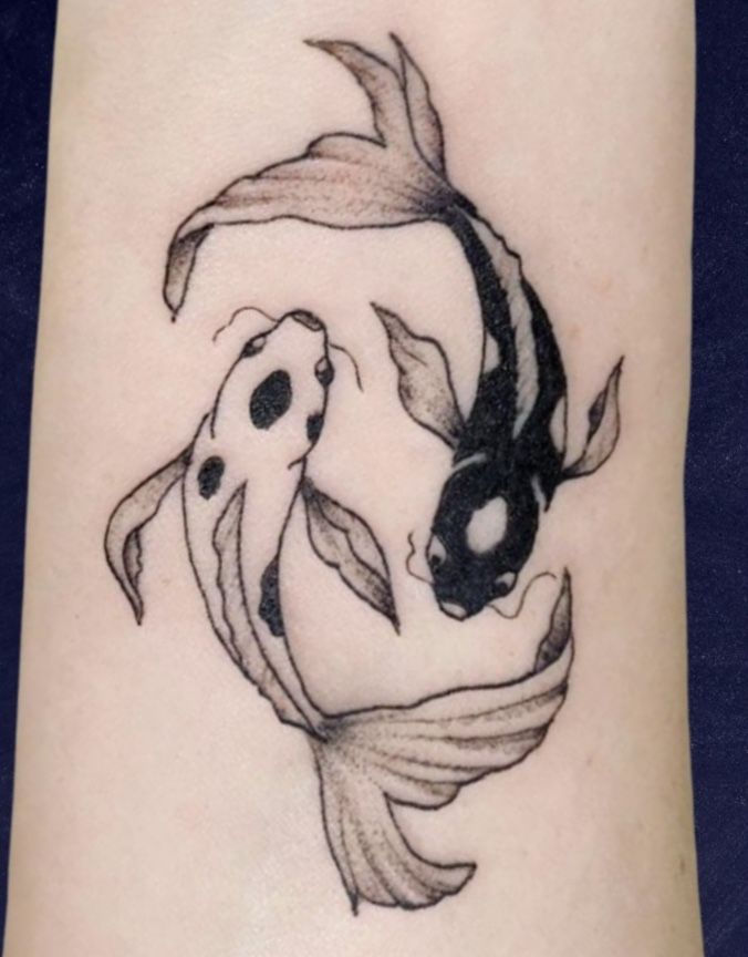 a black and white koi fish tattoo on the arm