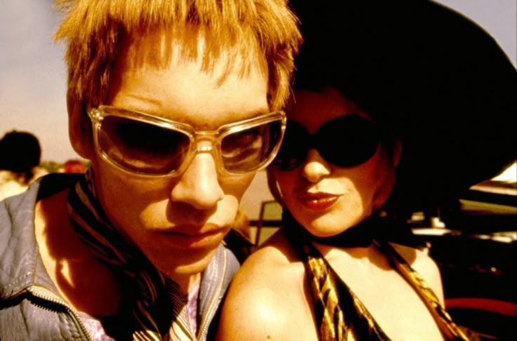 two people wearing sunglasses and hats posing for the camera