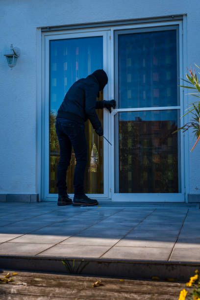 a person in a black hoodie is using a window to open the front door