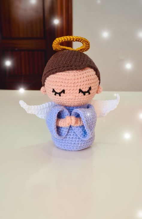 a crocheted doll with angel wings on top of a white table in front of some lights