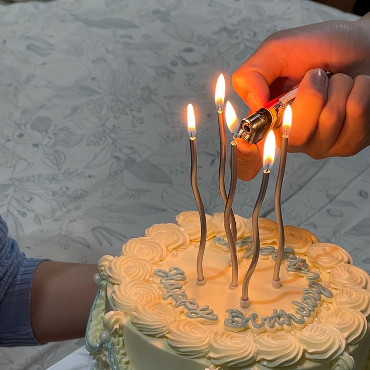 a person lighting candles on top of a cake