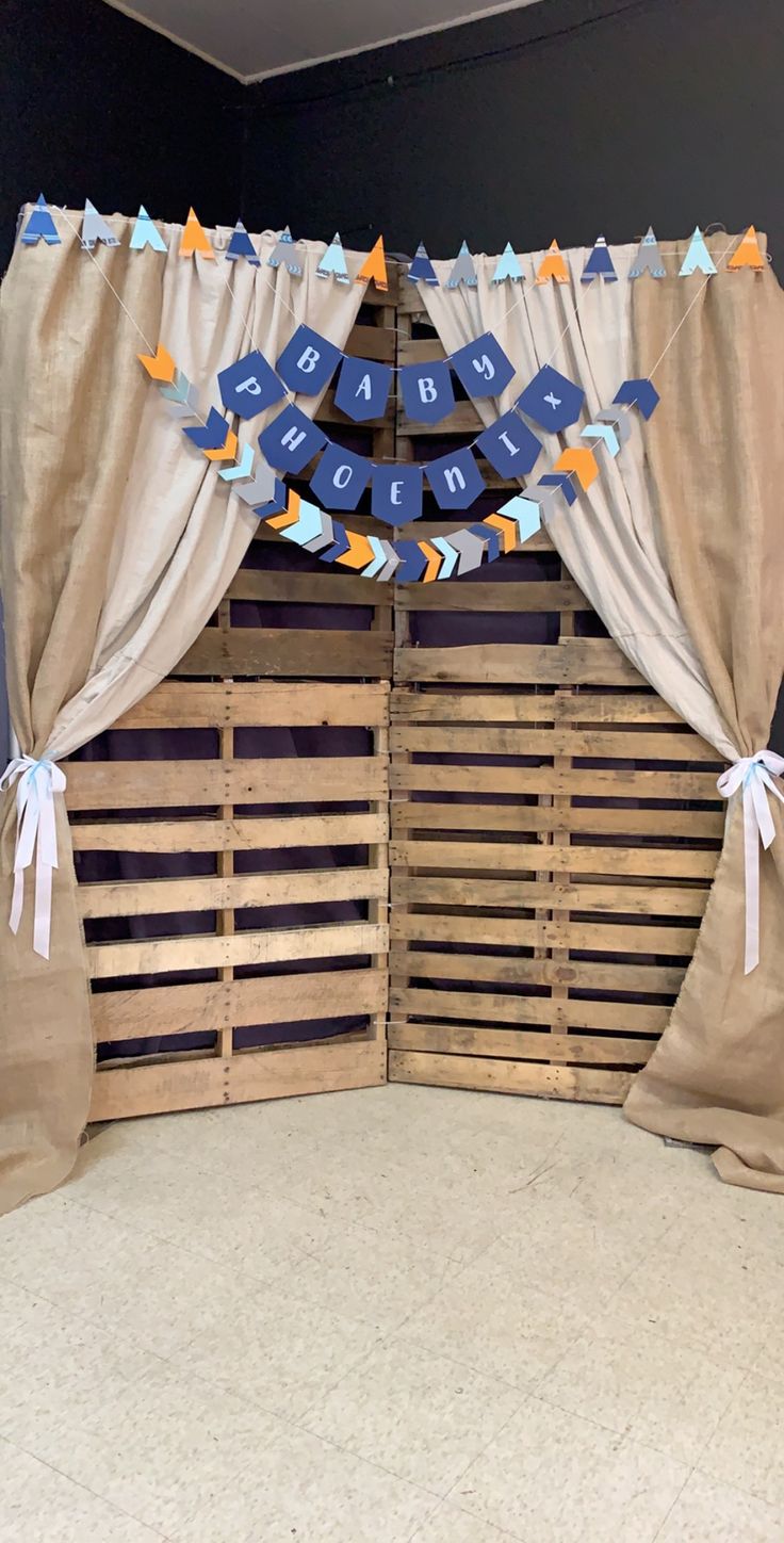 a room with some wooden pallets and curtains on the wall, decorated in blue and orange