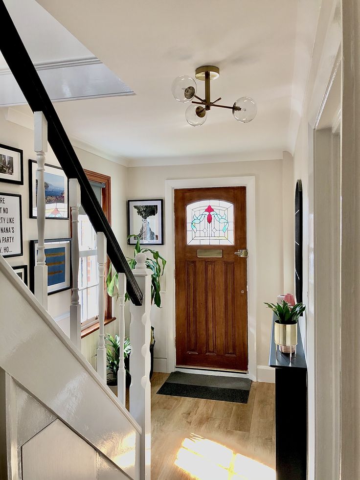 an entryway with stairs and pictures on the wall, framed by wood door frames