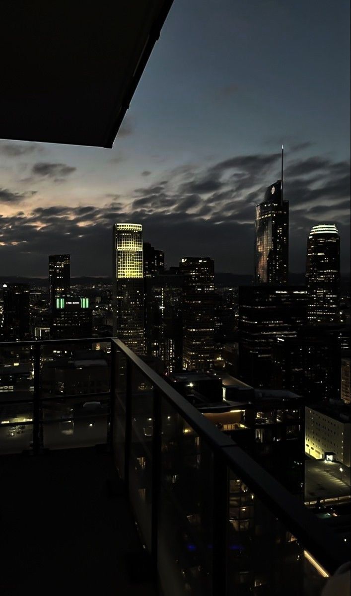 the city skyline is lit up at night, with skyscrapers in the foreground