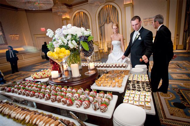 a man and woman standing in front of a table full of desserts on it