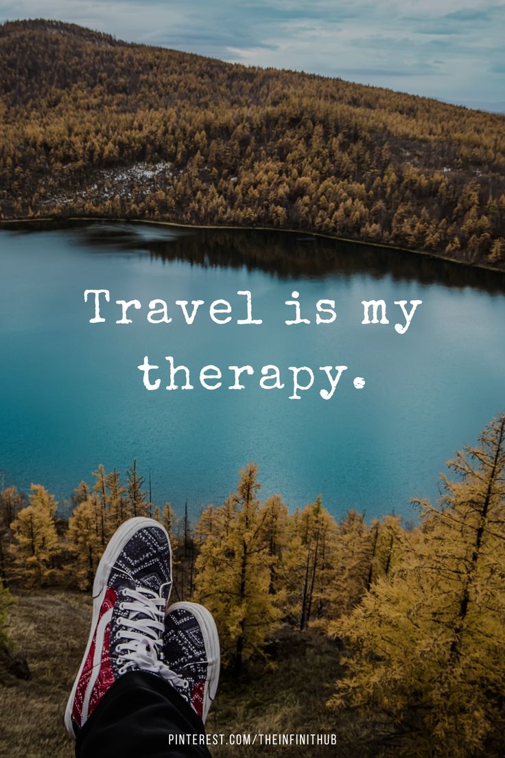 a person's feet with the words travel is my therapy in front of a lake