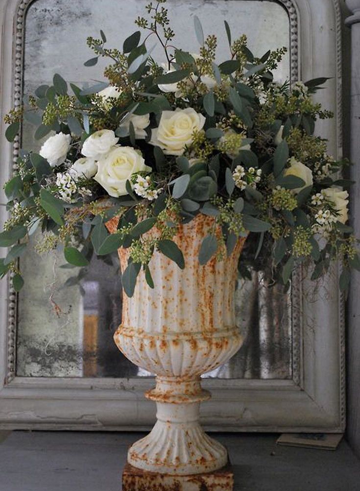 a vase filled with white flowers sitting on top of a table next to a mirror