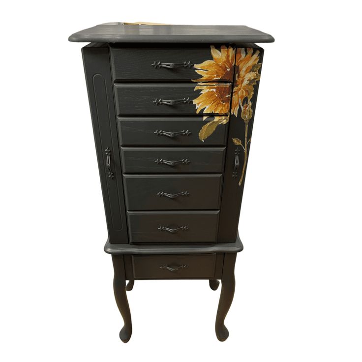 a black cabinet with sunflowers painted on the front and bottom drawers, sitting against a white background