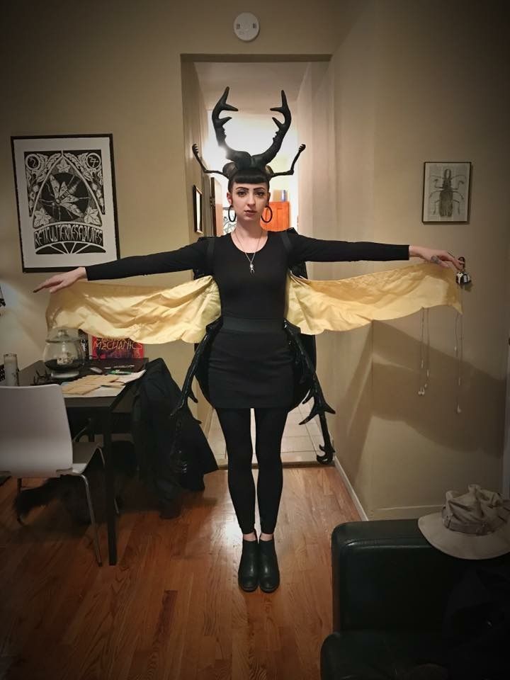 a woman with horns on her head is standing in a living room wearing black and yellow