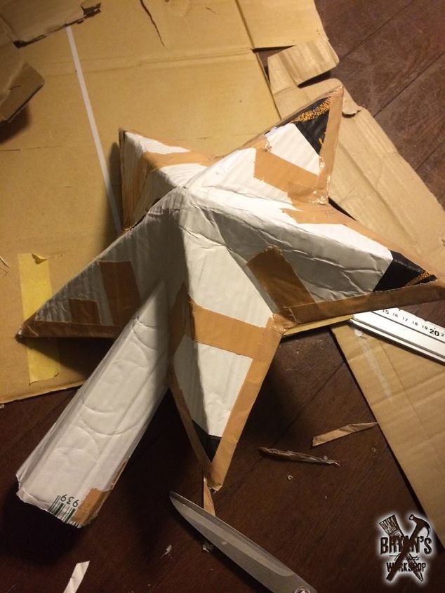 an airplane made out of cardboard sitting on top of a table next to some scissors