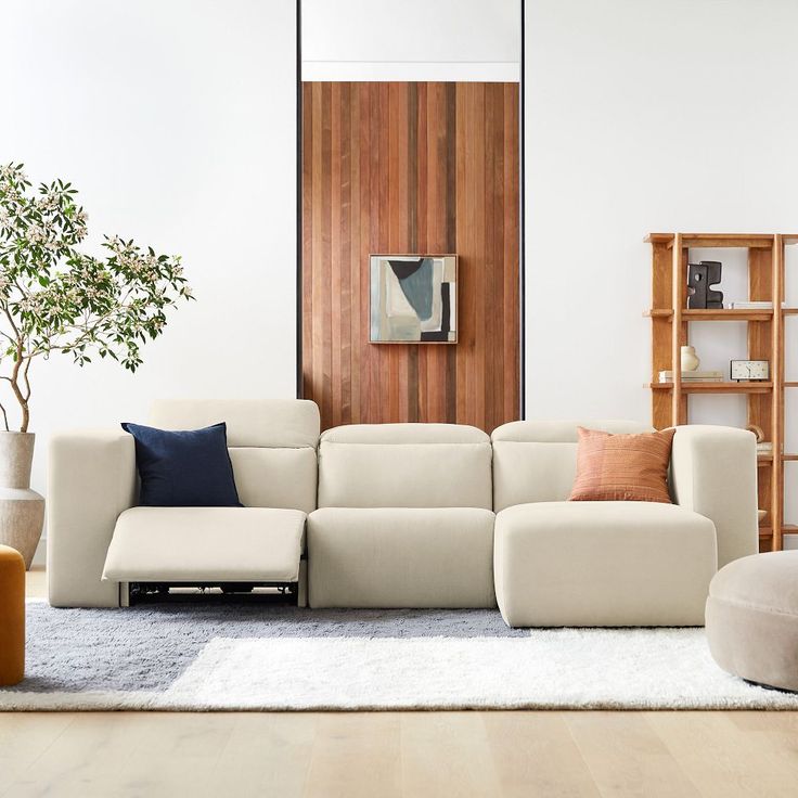 a modern living room with white furniture and wood paneling on the wall behind it