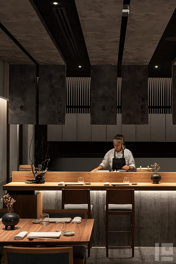 a man sitting at a table in front of a counter with sushi on it