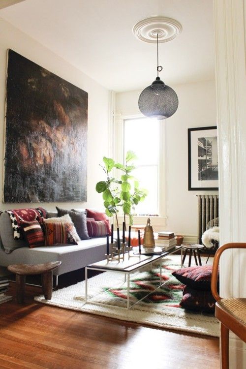 a living room filled with furniture and a large painting hanging on the wall above it