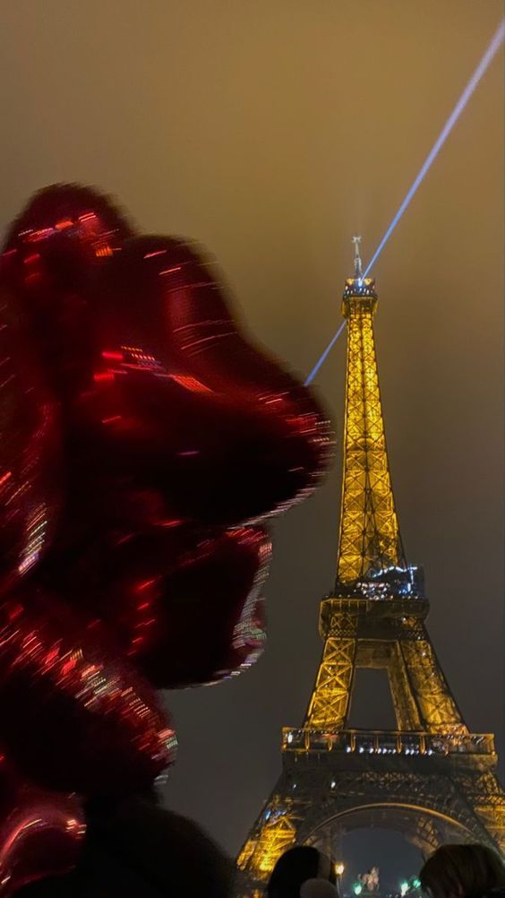 the eiffel tower is lit up at night with red lights on its face