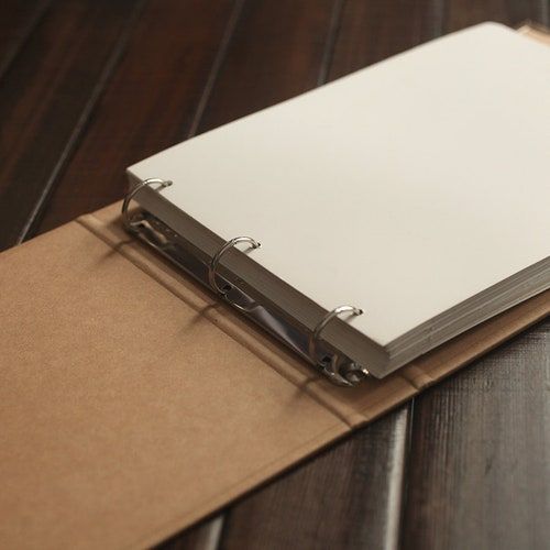 a binder on top of a wooden table next to a notepad and pen