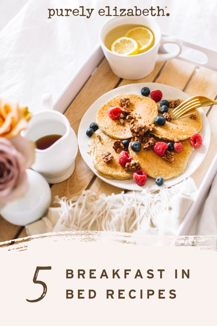 pancakes with berries and granola on a tray next to coffee, orange juice and flowers