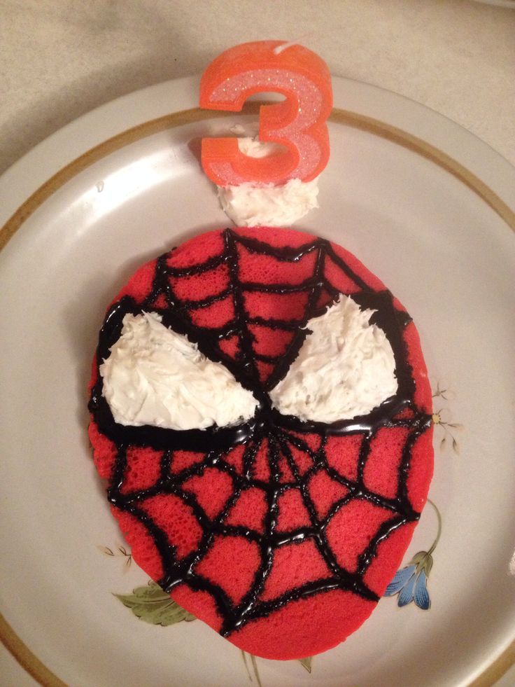 a spiderman cake on a white plate with the number three in the middle and frosting