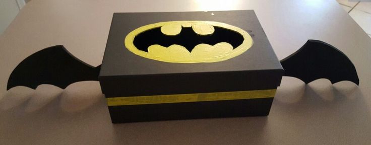 a black box with a yellow batman symbol on the front and bottom, sitting on a table