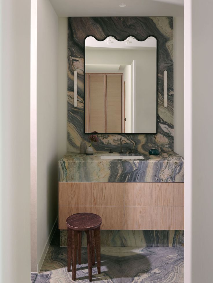 a bathroom with marble counter tops and wooden cabinets, along with a stool in front of the mirror