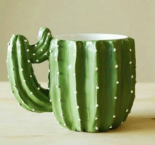 a green cactus mug sitting on top of a wooden table