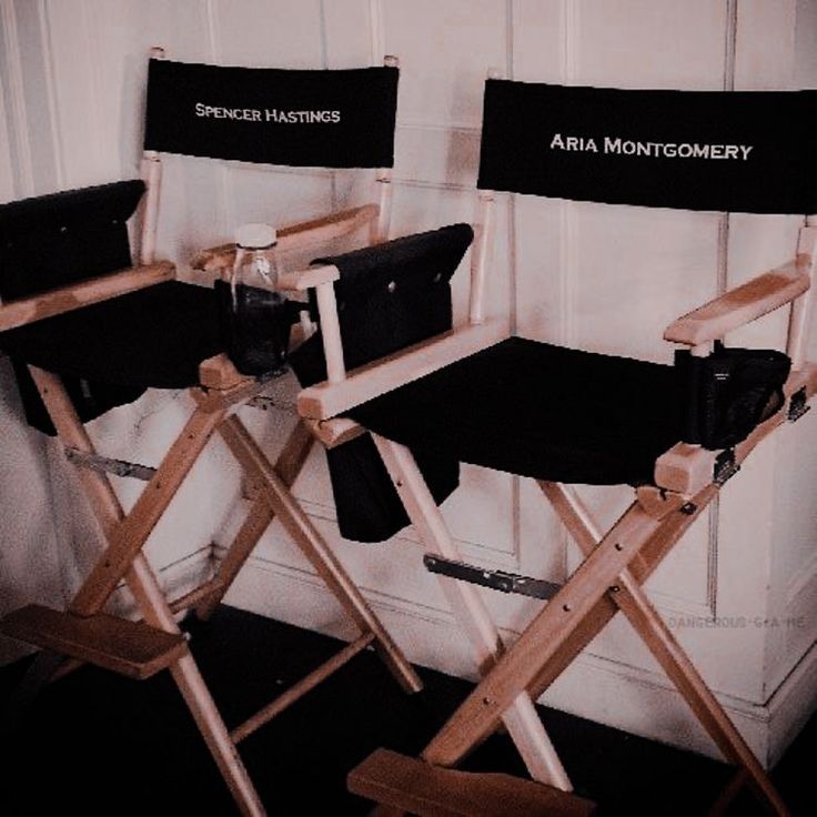 two director's chairs sitting next to each other in front of a white wall