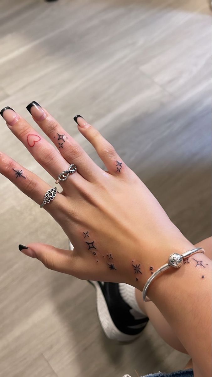 a woman's hand with stars and moon tattoos on it