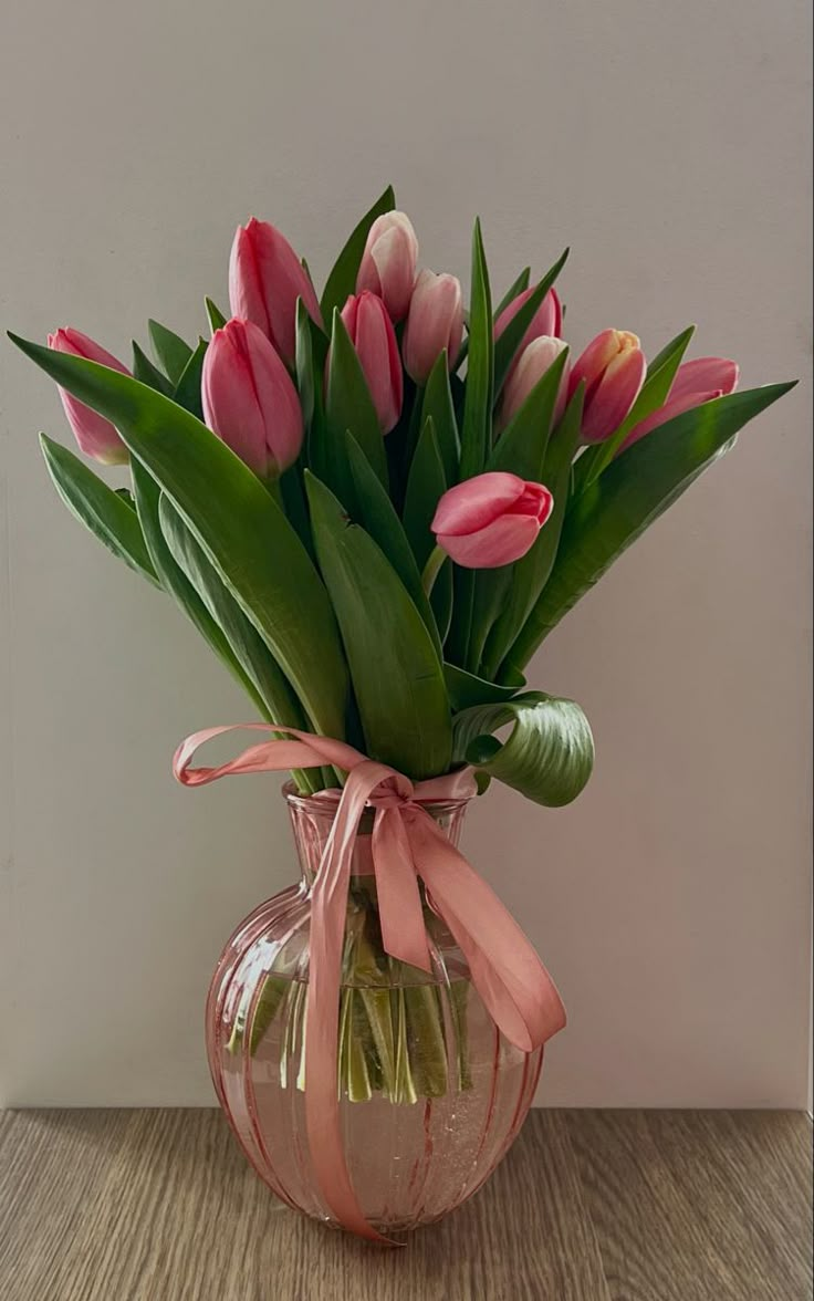 a vase filled with pink tulips on top of a wooden table