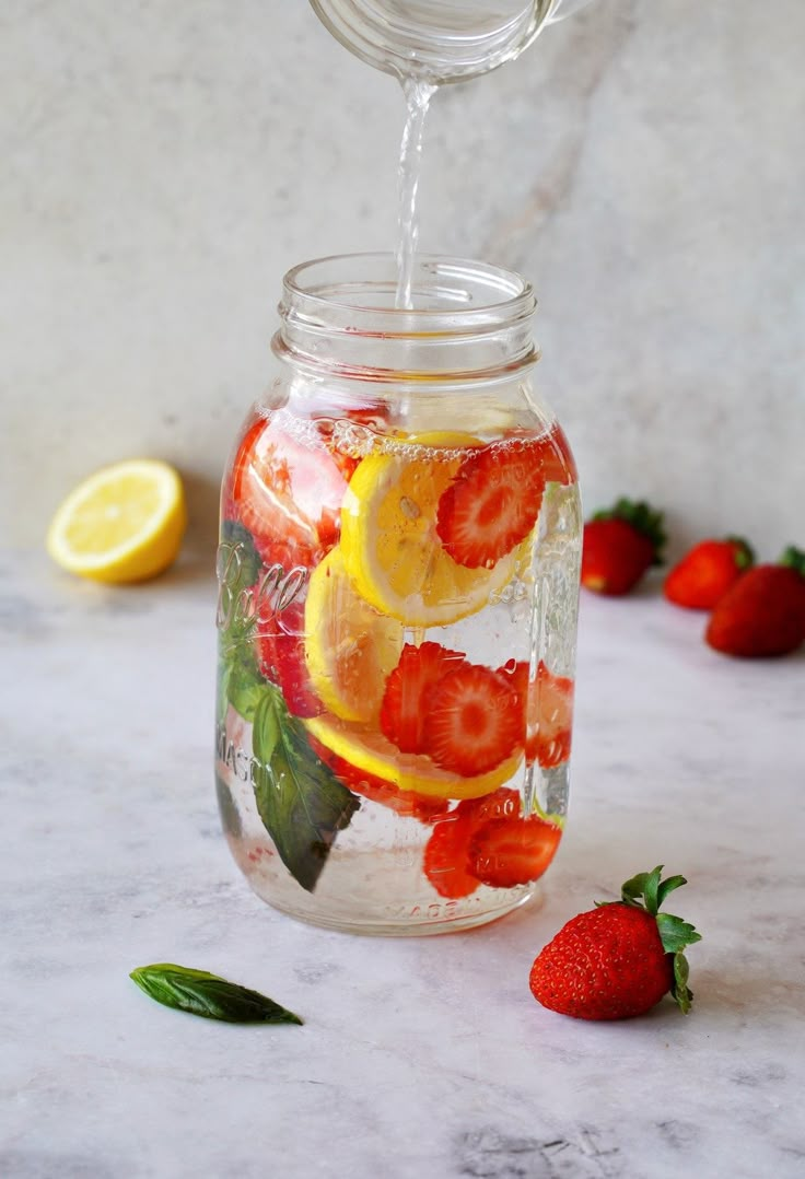 a mason jar filled with sliced strawberries and lemons