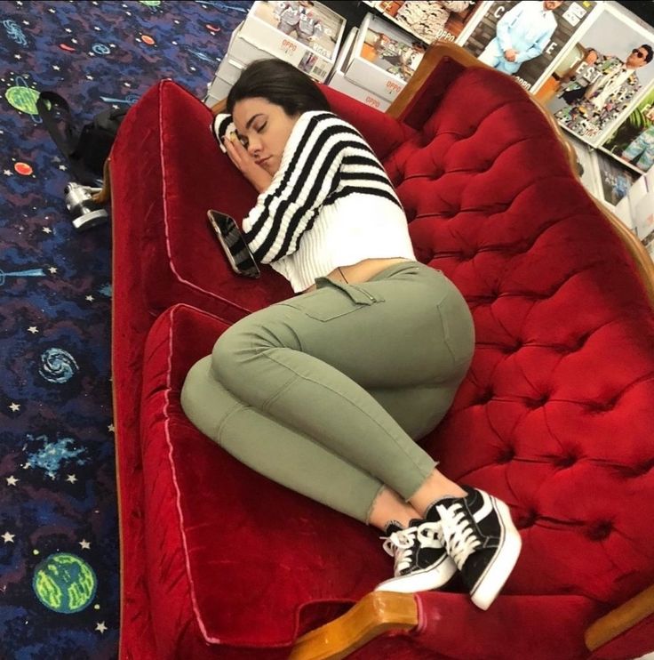 a woman laying on top of a red couch