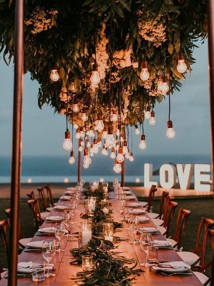 a long table is set up with candles and greenery for an outdoor wedding reception