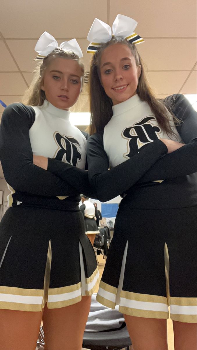 two girls dressed in cheerleader outfits posing for the camera with their hands on their hips