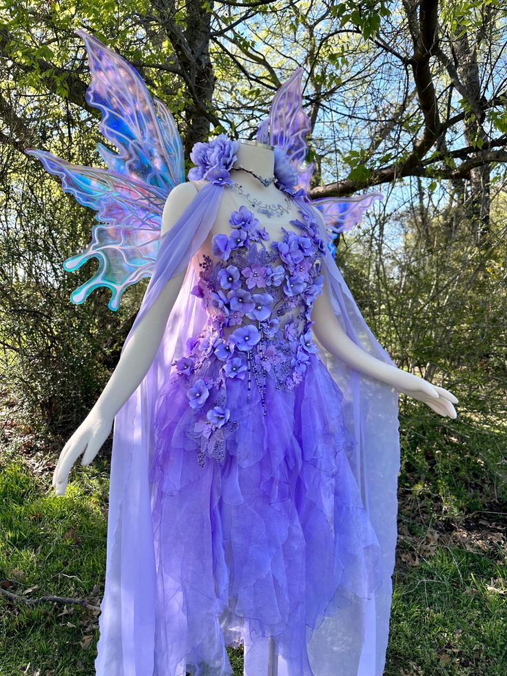 a purple and blue fairy costume on display in the grass