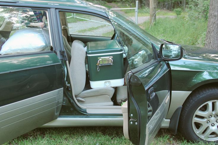 a green car with its door open sitting in the grass