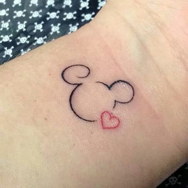 a small mickey mouse tattoo on the wrist with a heart in it's center