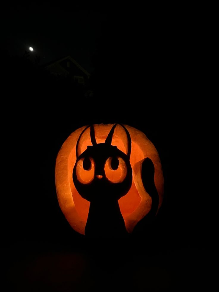 a pumpkin carved to look like a cat with big eyes and horns on it's head