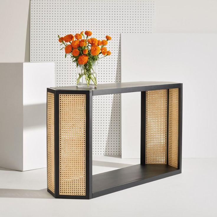 a vase filled with orange flowers sitting on top of a wooden table next to two white cubes