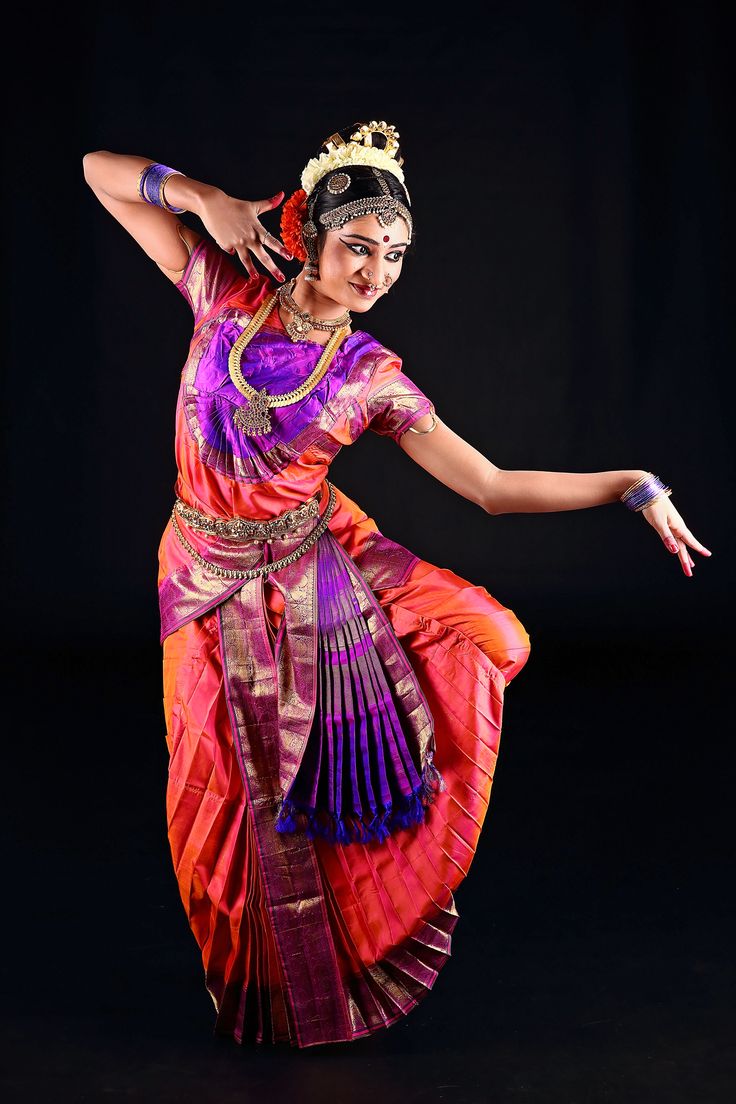 a woman in an orange and purple sari dancing