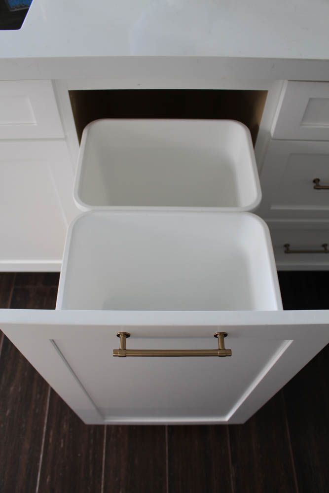 an open drawer in a kitchen with wooden flooring and white cabinetry on the side