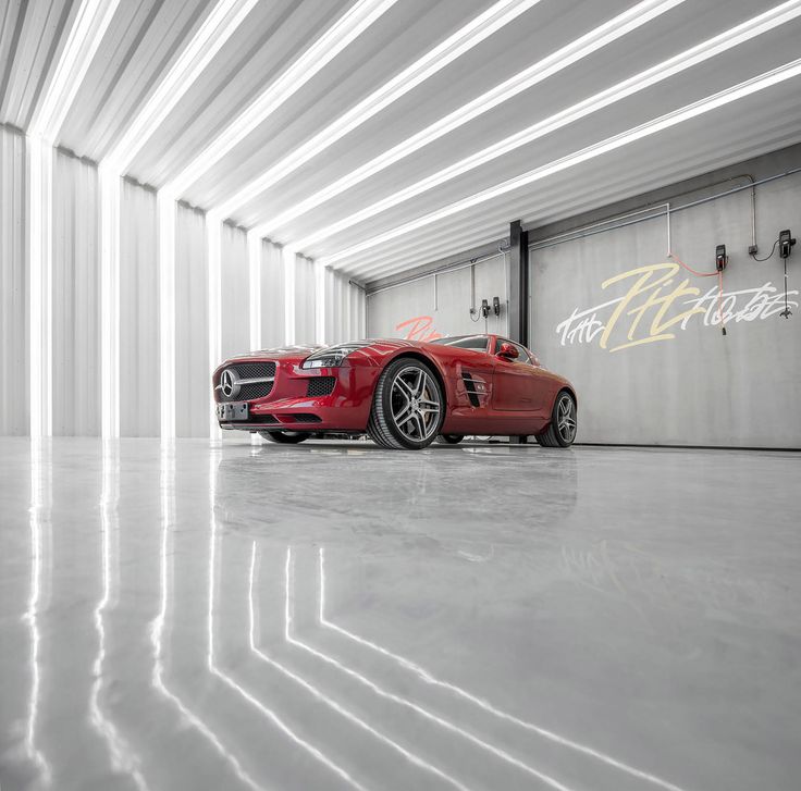 a red sports car is parked in an empty garage with white walls and flooring