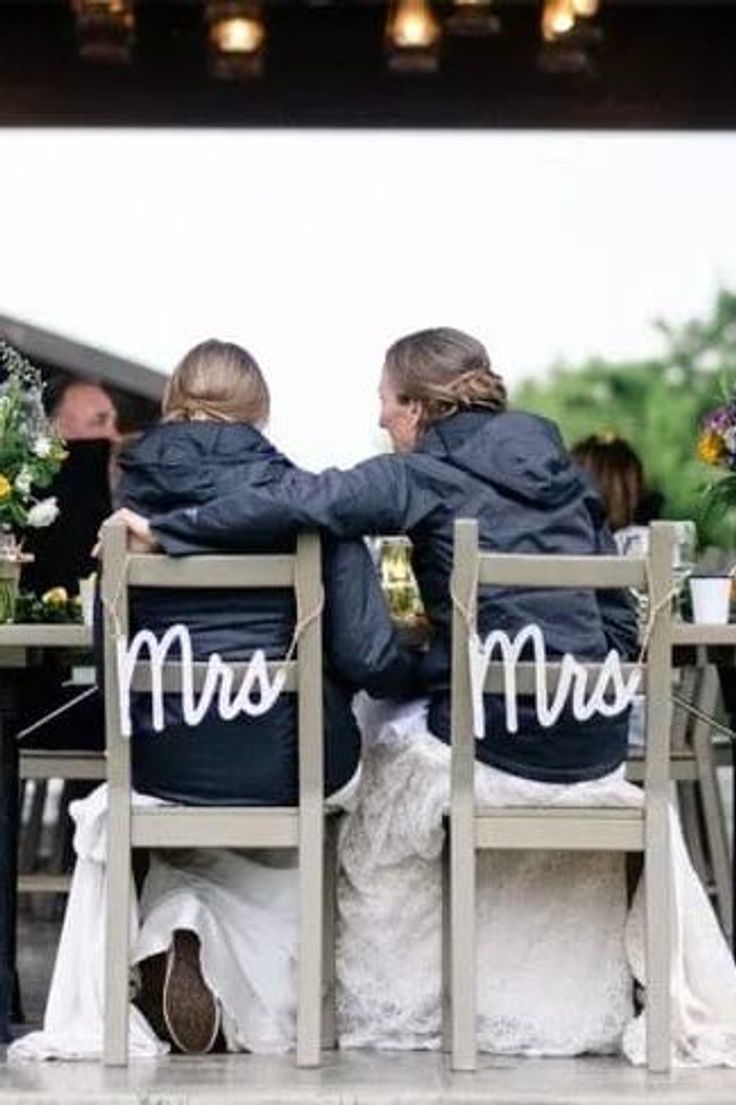 two people sitting at a table with their backs to each other, wearing jackets that say mr and mrs