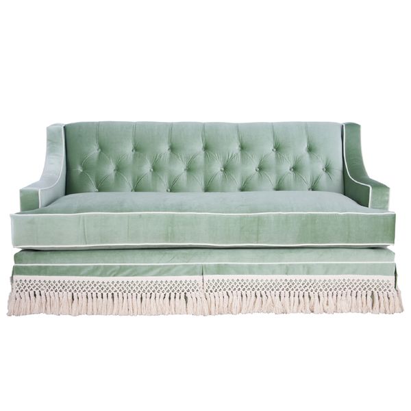 a green velvet couch with fringe trim