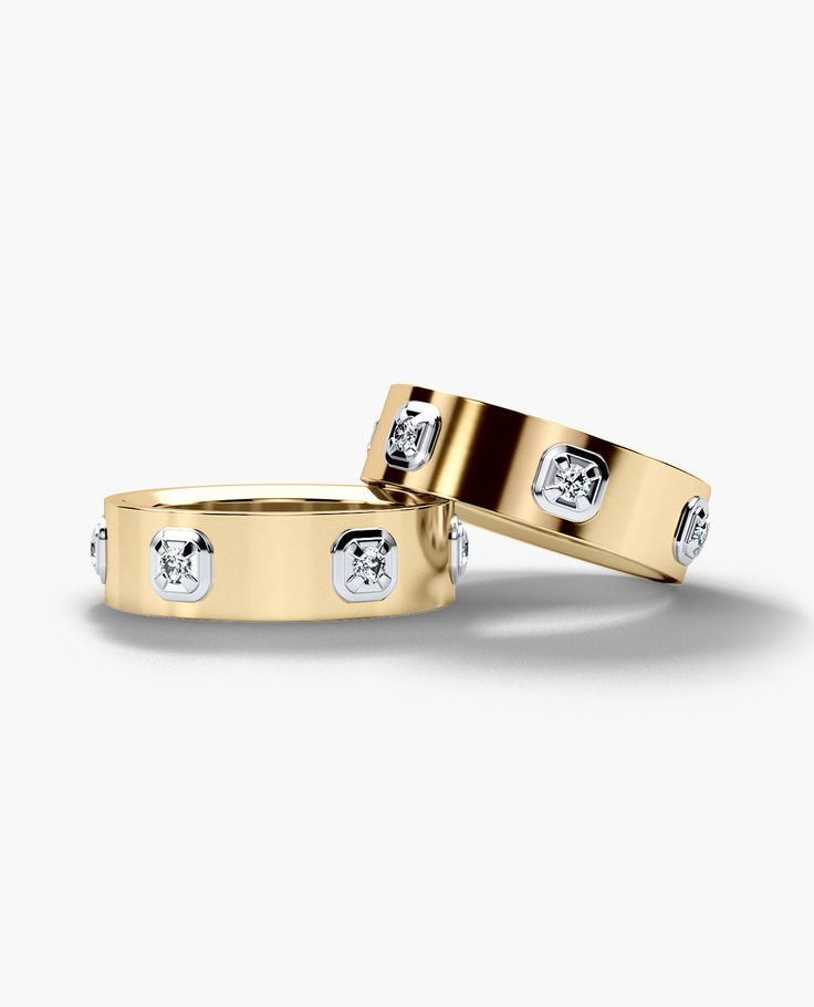 two yellow gold wedding bands with diamonds on each side, set against a white background