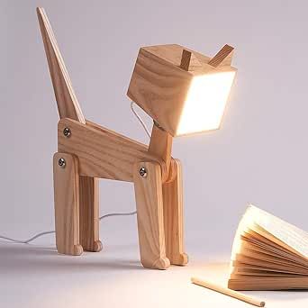 a wooden dog lamp sitting on top of a table next to an open book with a light coming from it