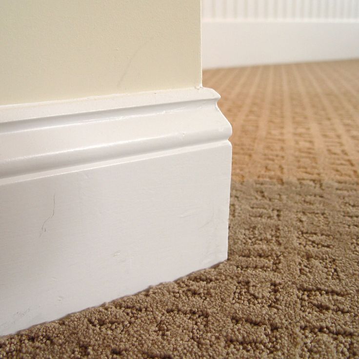 the corner of a room with carpeting and white trim on the wall next to it