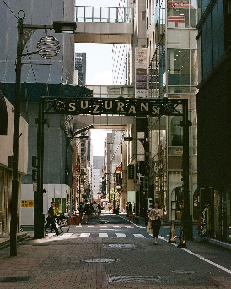 people are walking down the street under an overpass that reads suzuransk