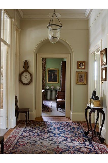 a hallway with an ornate rug and paintings on the walls