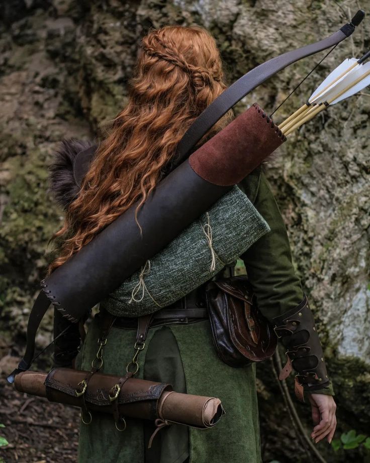 a woman with long red hair holding a bow and arrow