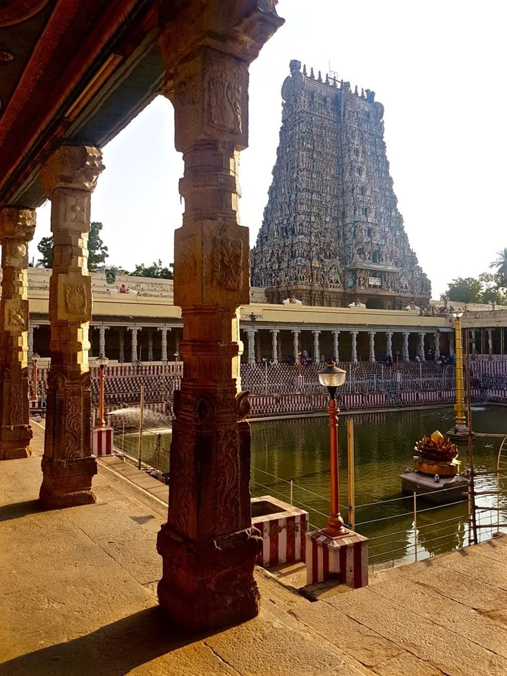 the temple is surrounded by water and pillars with statues on them in front of it